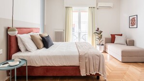A modern bedroom with a bed, bedside table, and a sofa. - Petite 1BR Apartment in Exarchia (Athens)
