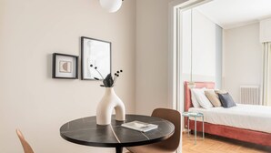 A modern bedroom with a bed, a small table with a vase, and two framed pictures on the wall. - Petite 1BR Apartment in Exarchia (Athens)