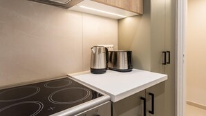 A compact kitchen with a built-in stove, a coffee maker, and a toaster. - Petite 1BR Apartment in Exarchia (Athens)
