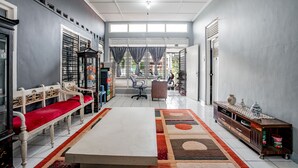 A spacious room with a long white table, a red bench, and a patterned rug.