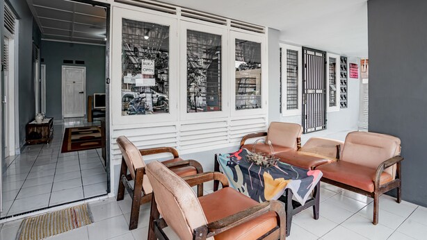 A room with a dining table and four chairs, a window with a view of the street, and a door leading to another room.