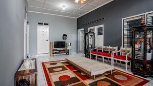A living room with a sofa, a television, a coffee table, and a decorative cabinet.