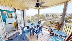 A balcony with a table and chairs, a ceiling fan, and a view of a swimming pool and buildings. - Spectacular Penthouse Oasis with Mesmerizing Ocean Views (Isle of Palms)