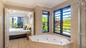 Une salle de bain moderne dotée d’une grande baignoire, d’un espace douche et d’un balcon offrant une vue sur la verdure.