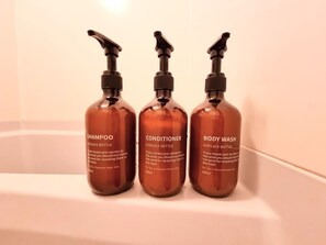 Three bottles of shampoo, conditioner, and body wash in a bathroom. - City Heights (Osaka)
