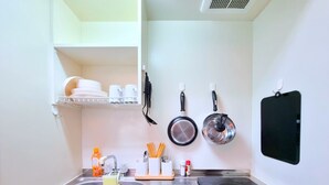 A compact kitchen with a sink, stove, and hanging utensils. - City Heights (Osaka)