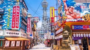 A bustling street with various shops and a prominent statue. - City Heights (Osaka)