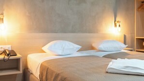 A hotel room with two beds, each with white pillows and a beige bedspread. There is a bedside table with a telephone and a wall-mounted light fixture. - Athens Hawks Urban (Athens)