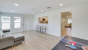 A modern living room with a grey sofa, two bar stools, a ping pong table, and a kitchen area in the background. - 3 Mi to Old Town: Home w/ Game Room in Scottsdale! (Scottsdale)