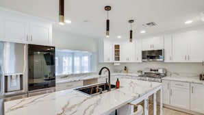 A modern kitchen with white cabinets, a marble countertop, stainless steel appliances, and pendant lighting. - 3 Mi to Old Town: Home w/ Game Room in Scottsdale! (Scottsdale)