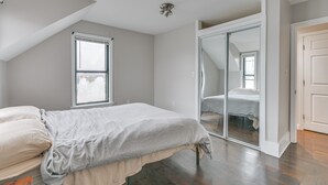 Une chambre à coucher avec un lit, une fenêtre et une porte-fenêtre coulissante donnant sur une autre pièce.
