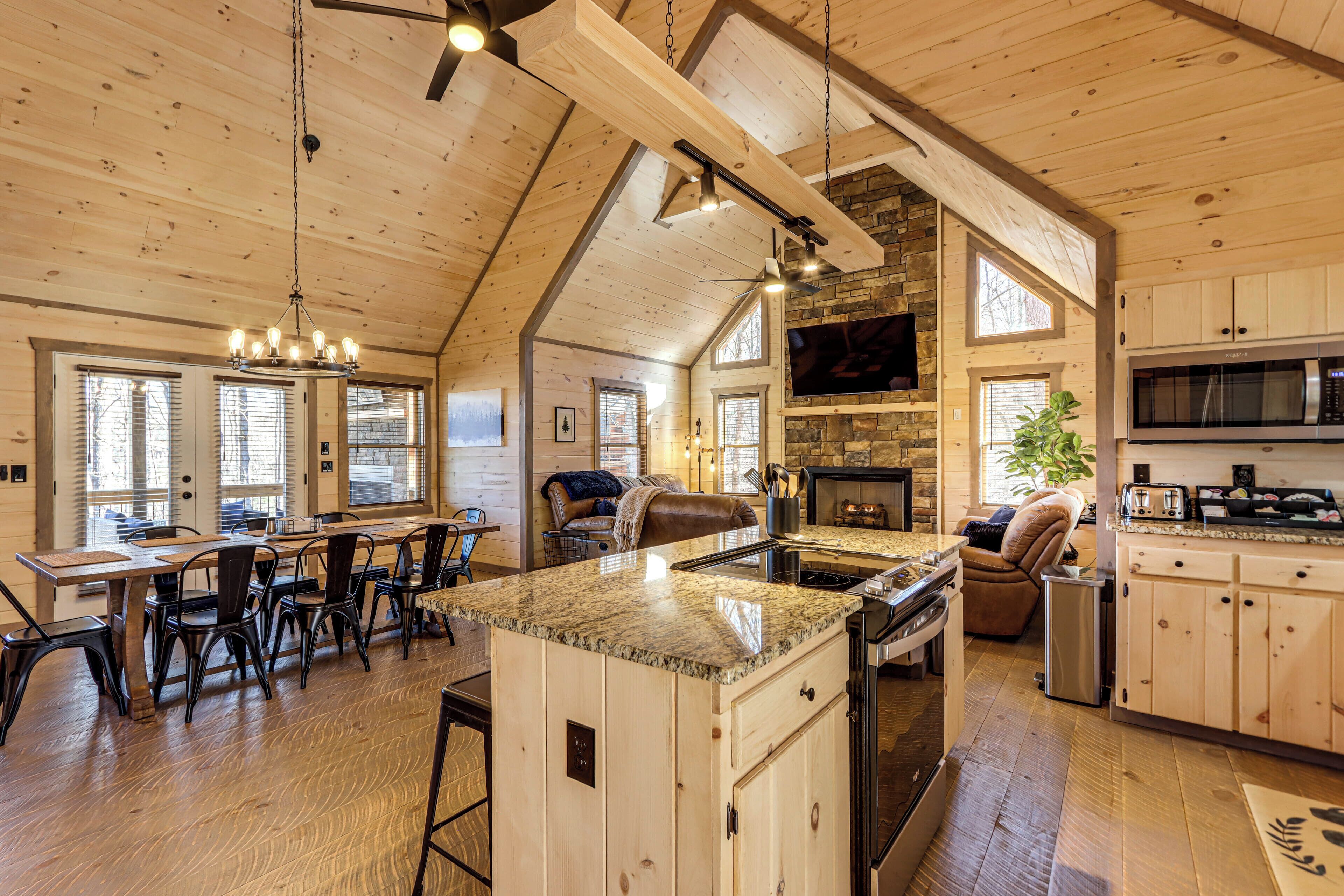 A spacious kitchen with a large island, wooden cabinets, and a stone fireplace.