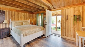 Ein Schlafzimmer mit Holzwand, einem Bett, einem Nachttisch und einer Tür, die zu einem Außenbereich führt.