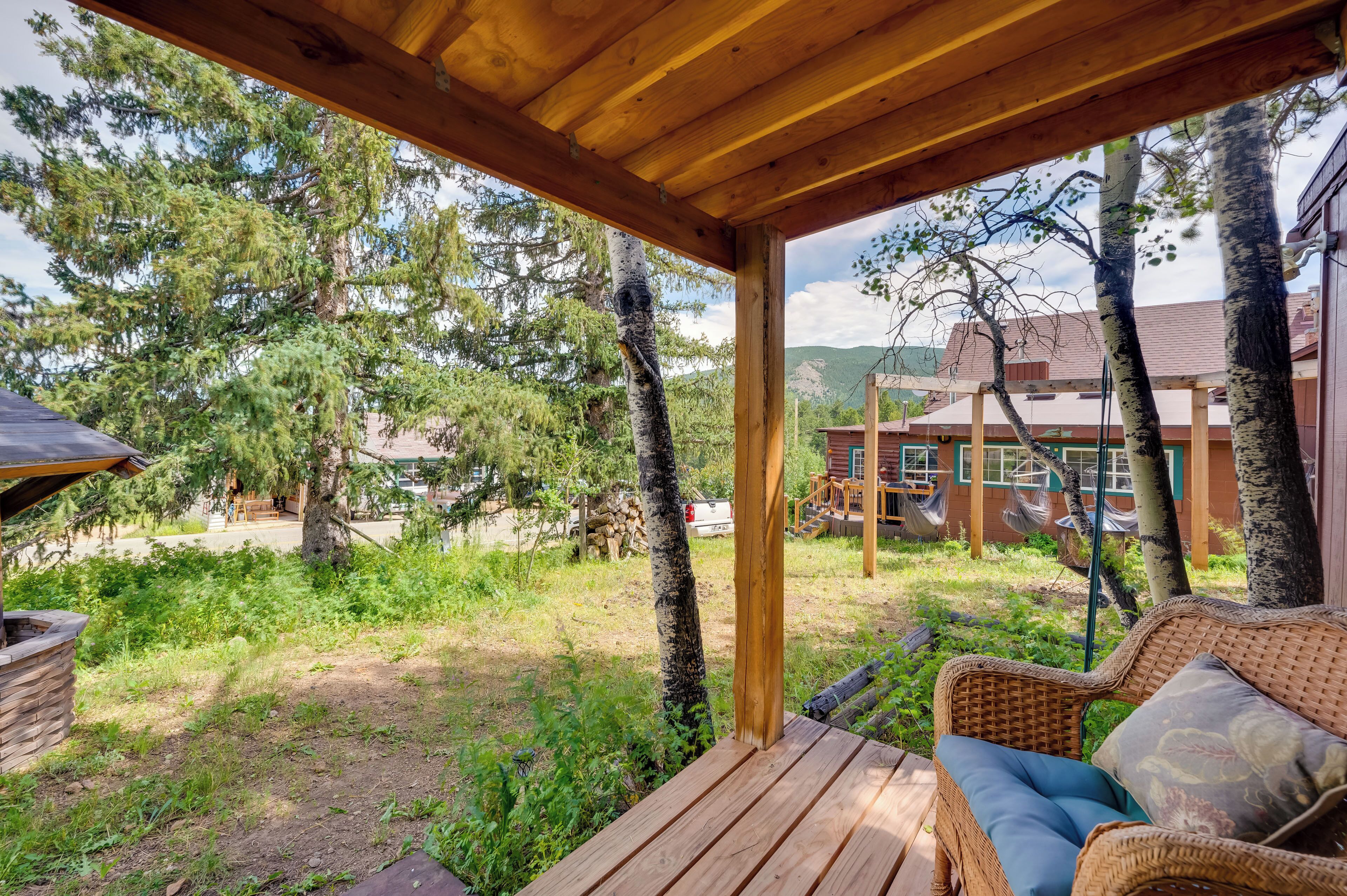 A wooden deck with a wicker sofa and a stone fireplace.