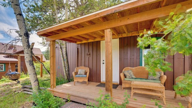 Eine Holzblockhütte mit Veranda, Korbmöbeln und einer Tür.