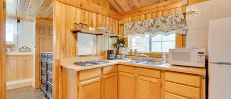 Una cocina de madera con microondas, un fregadero y armarios.