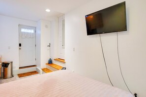 Un dormitorio con una cama, un televisor fijado a la pared, una puerta y una escalera.