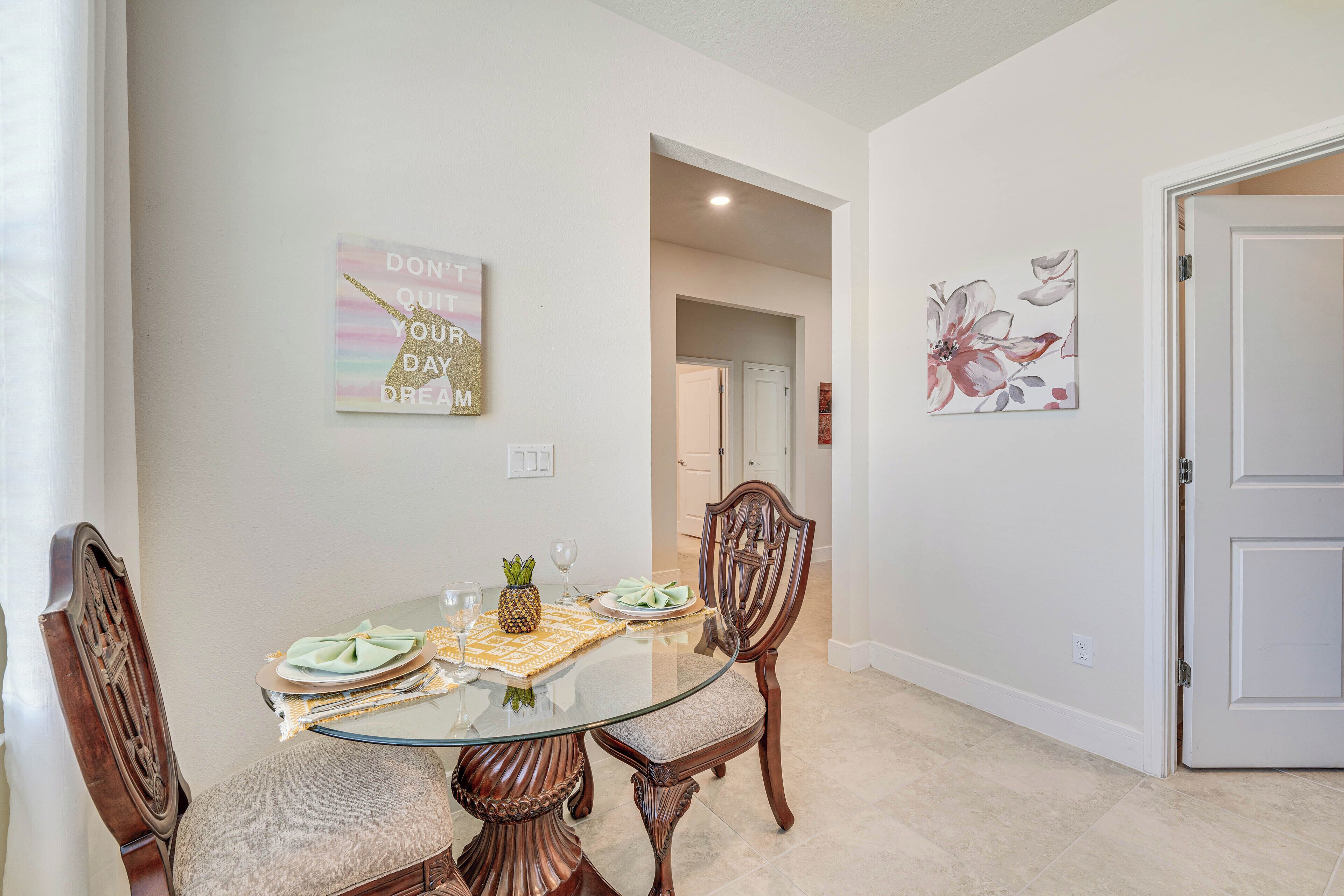 A dining area with a glass table, wooden chairs, a decorative wall piece, and a door.