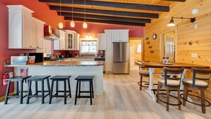 Una cocina con una isla central, taburetes de bar y una mesa de comedor con sillas.