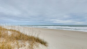 A beach with sand dunes and the ocean in the background.