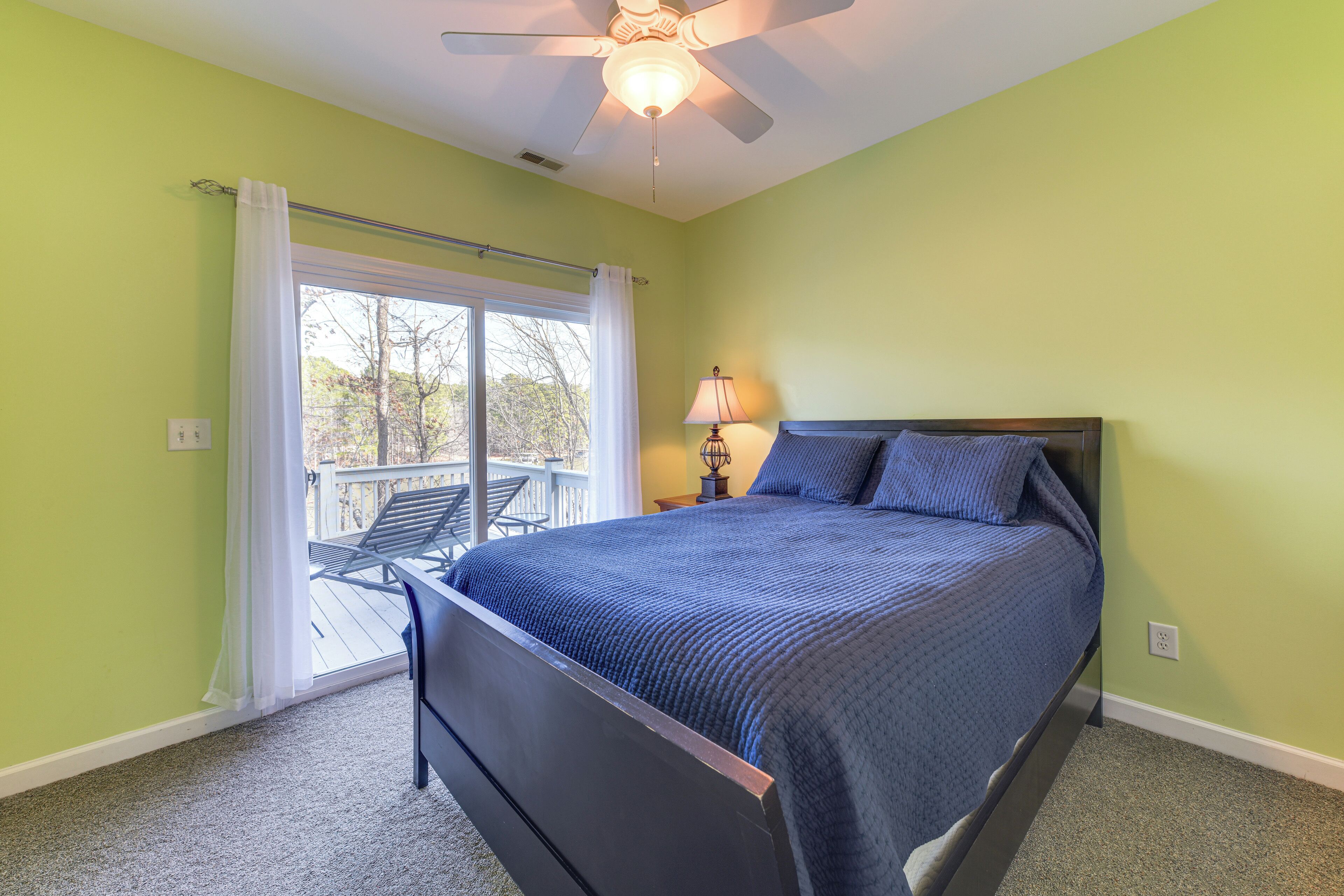 Une chambre à coucher avec un lit, un ventilateur de plafond, une lampe et une vue sur l’extérieur grâce à une porte coulissante.