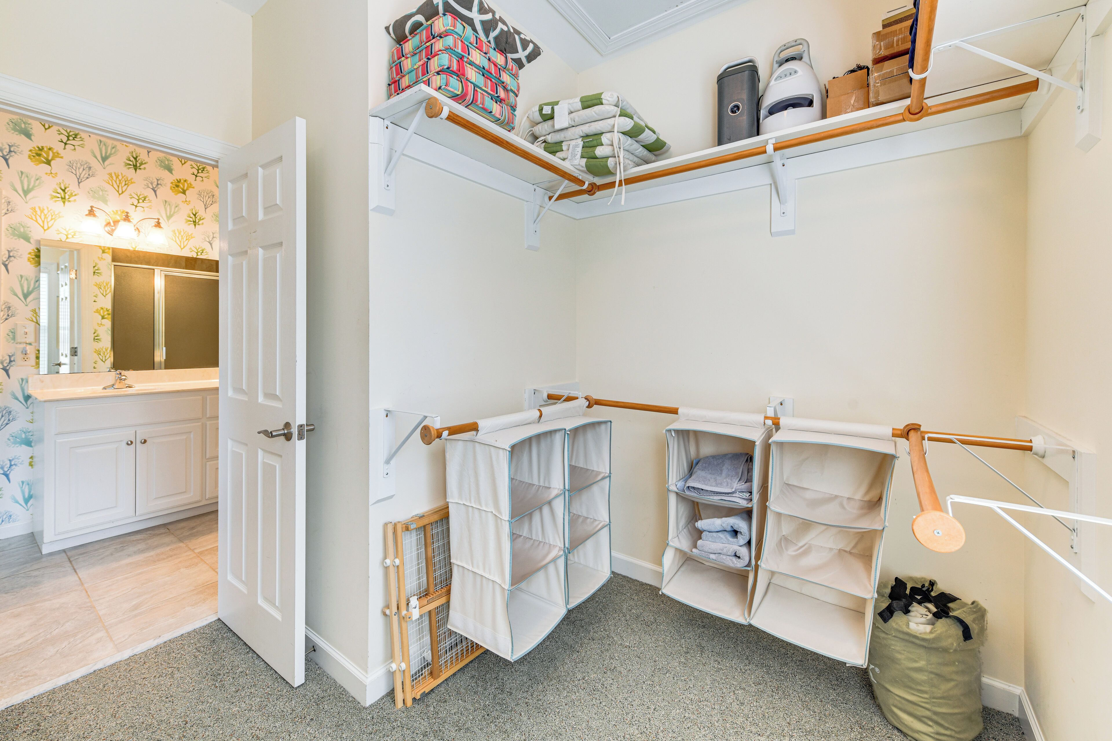 A laundry room with shelves, a drying rack, and a trash bin.