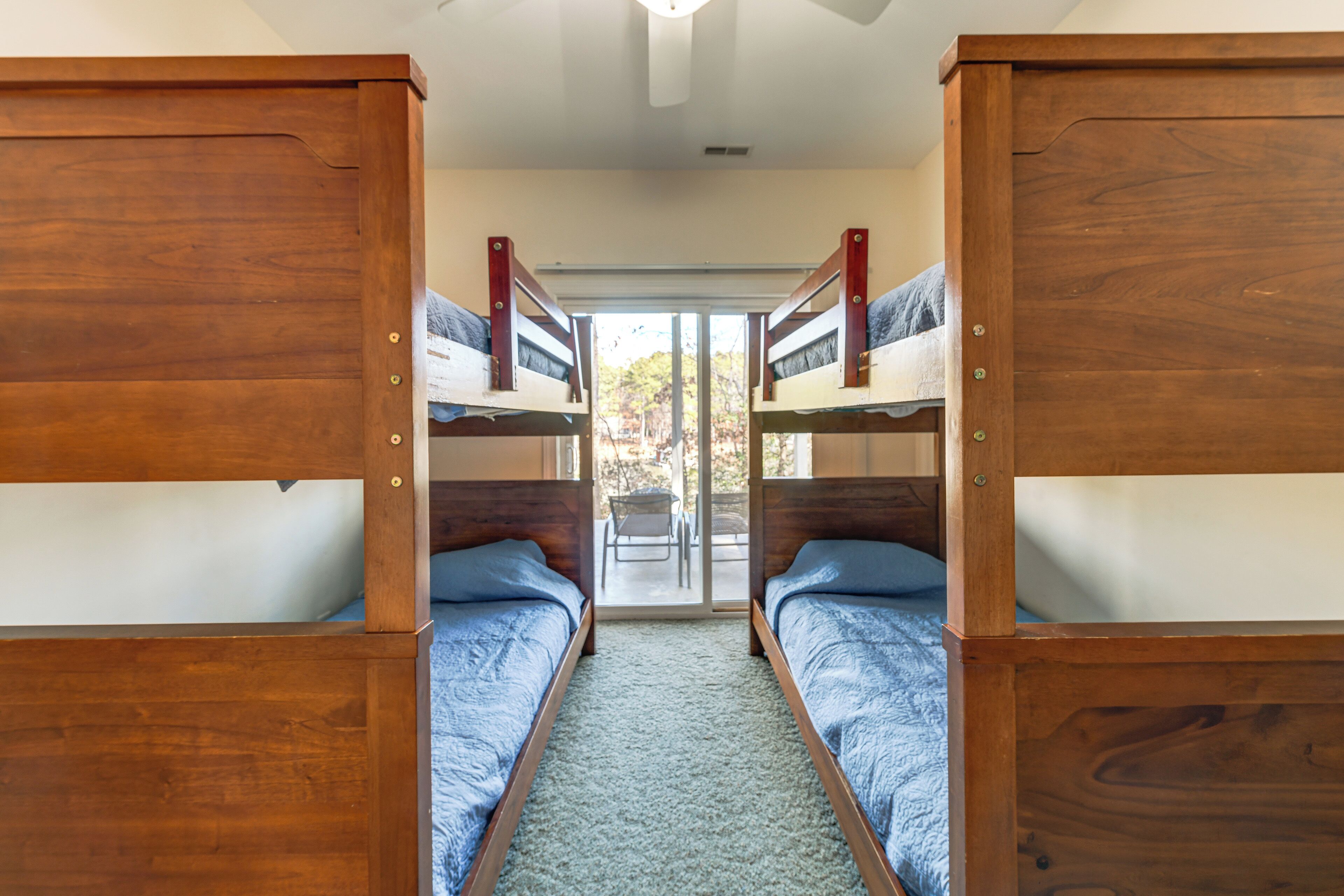 A room with two bunk beds, a sliding door leading to an outdoor area, and a ceiling fan.