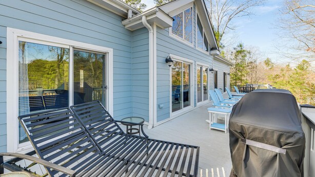 Une terrasse extérieure couverte, équipée d’un barbecue, de chaises longues et d’une table.