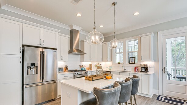 A modern kitchen with white cabinetry, stainless steel appliances, and a central island with bar stools. - Stunning Santa Rosa Beach Home, 1/2 Mi to Ocean! (Santa Rosa Beach)