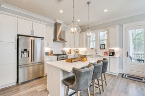 A modern kitchen with white cabinetry, stainless steel appliances, and a central island with bar stools. - Stunning Santa Rosa Beach Home, 1/2 Mi to Ocean! (Santa Rosa Beach)