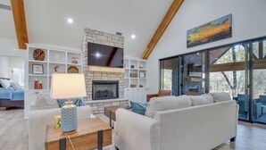 A modern living room with a fireplace, a television, and a large window. - Waterfront Flippin Retreat w/ White River Access! (Flippin)