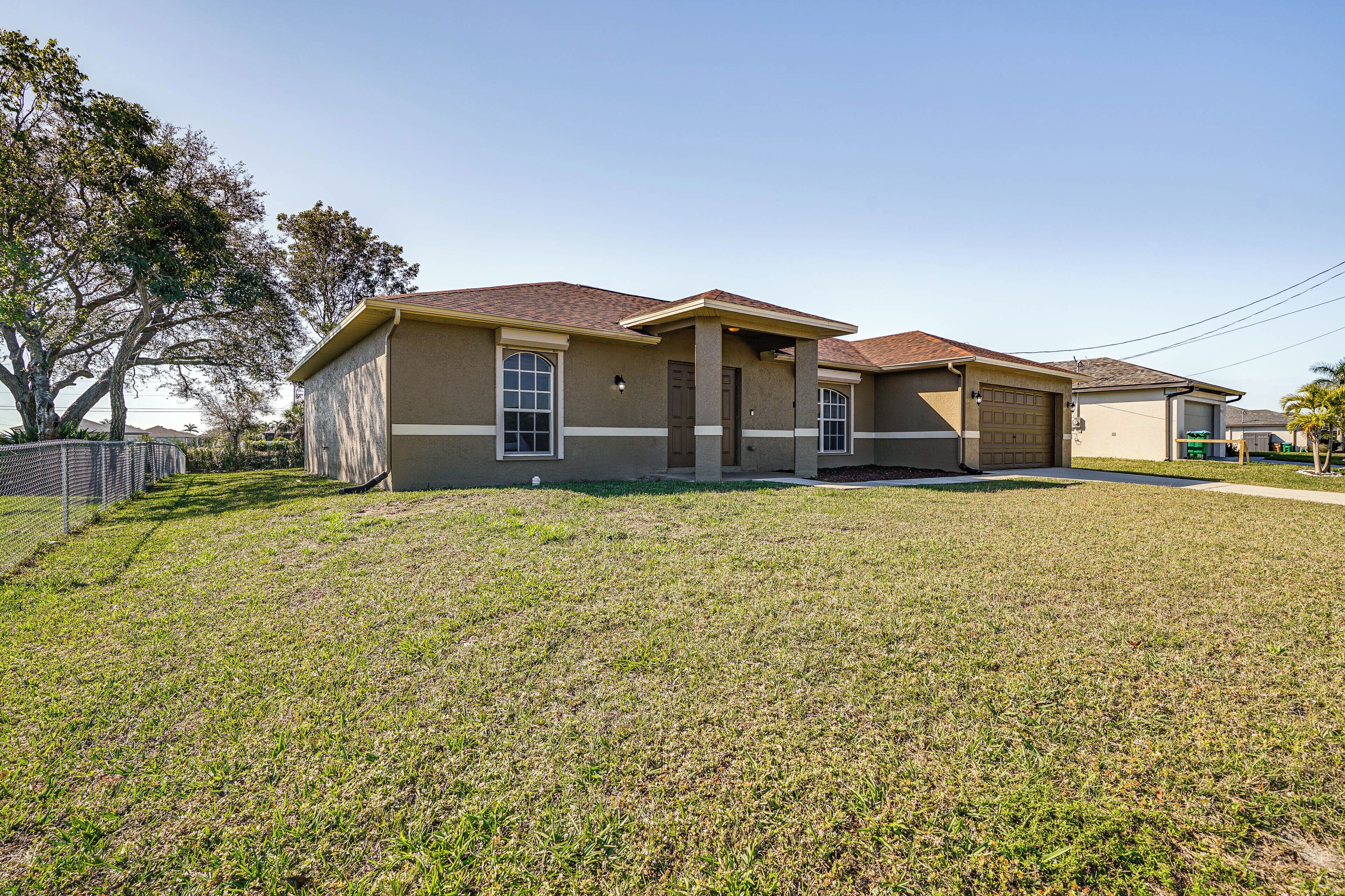 A two-story house with a garage, a front lawn, and a tree to the left.