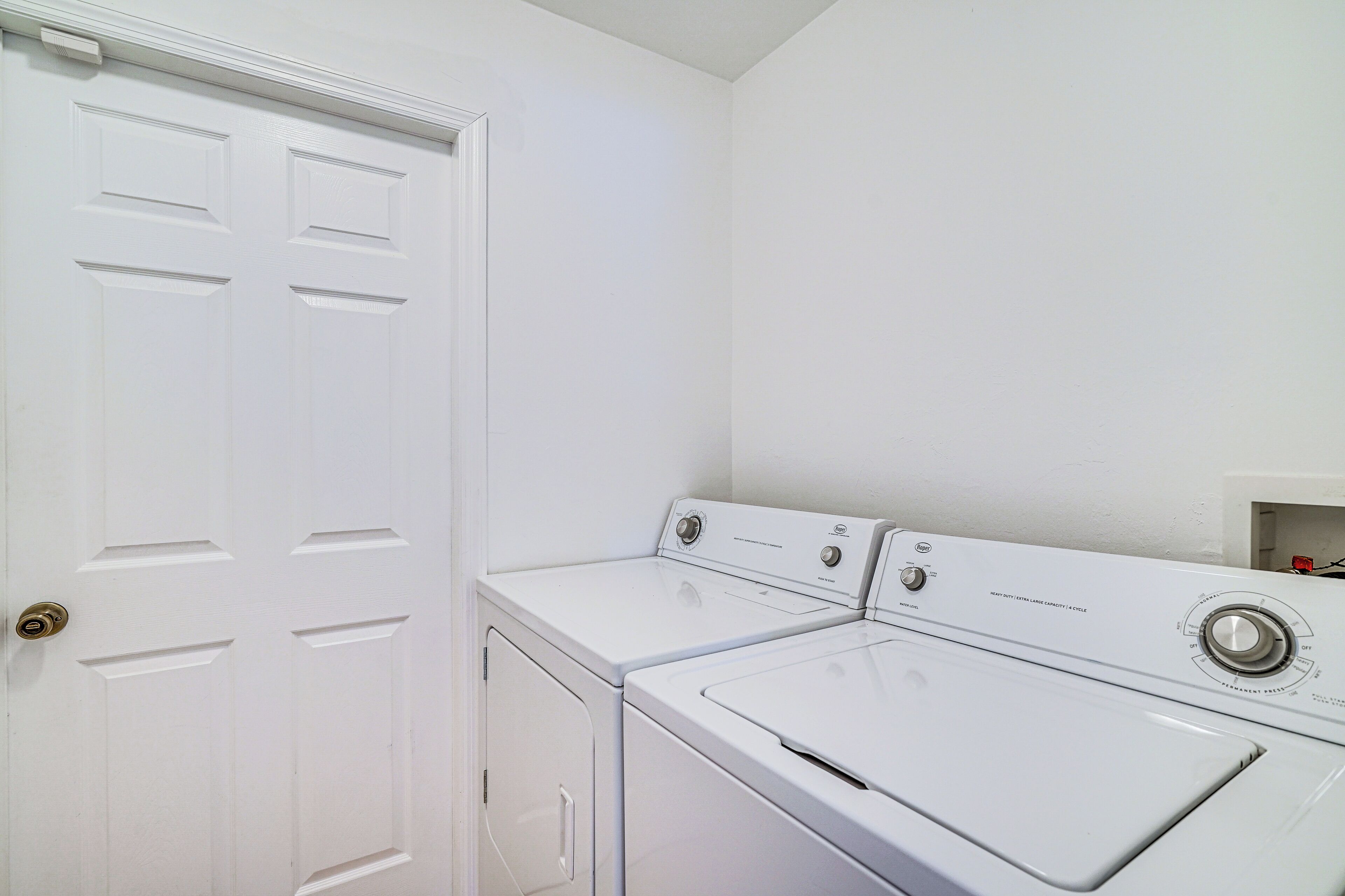 A laundry room with a white door and two stacked washers and dryers.