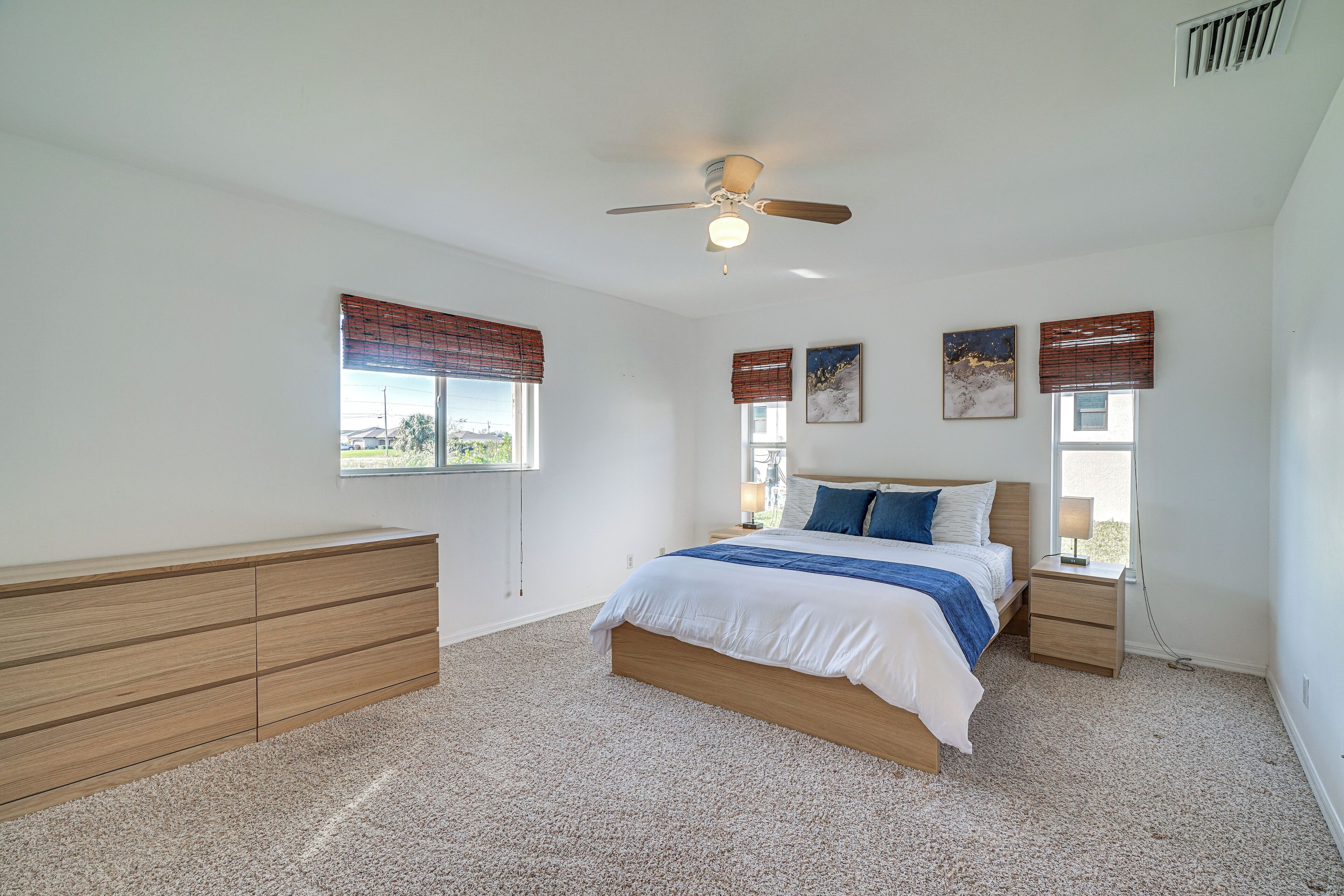 A bedroom with a bed, bedside tables, a ceiling fan, and a window with blinds.
