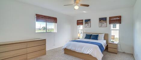 A bedroom with a bed, bedside tables, a ceiling fan, and a window with blinds.