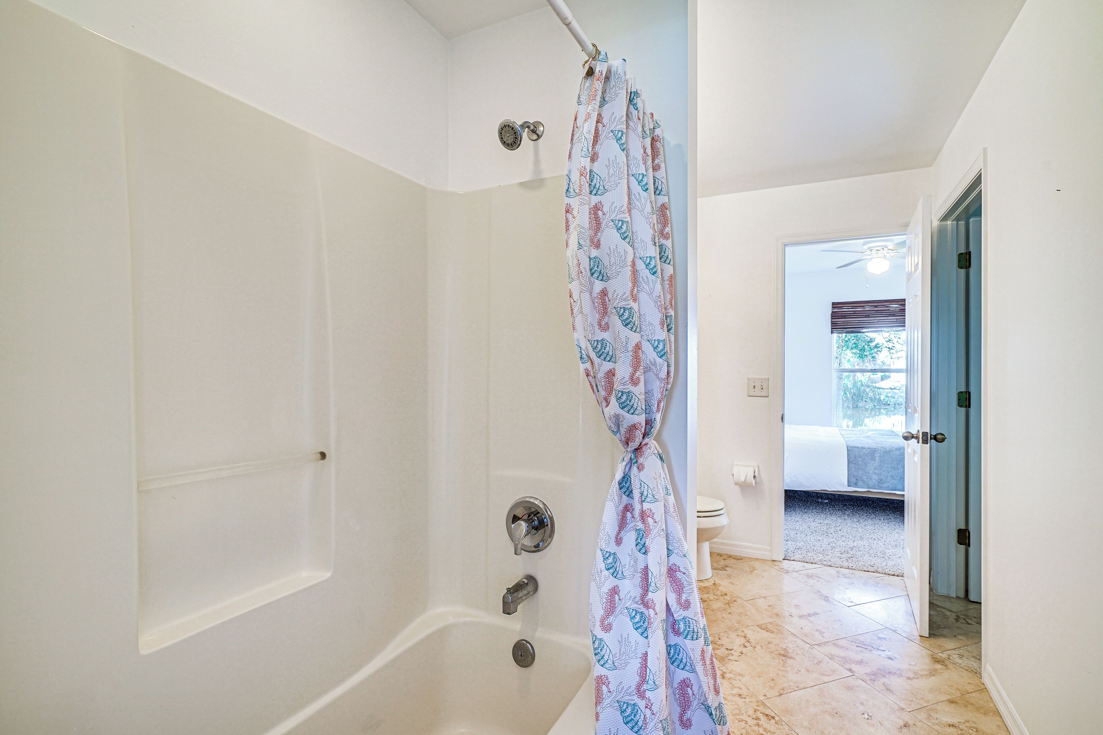 A bathroom with a bathtub, a shower curtain, and a toilet.