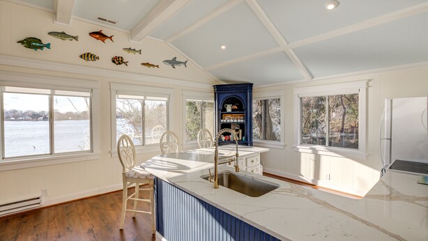 A kitchen with a large island, white cabinetry, and a view of the water.