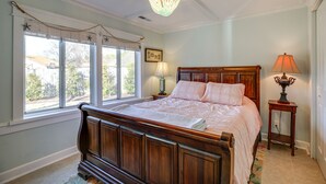 A bedroom with a wooden bed, a chandelier, a window with star decorations, and a lamp on a bedside table.