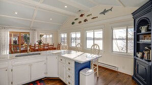 A kitchen with white cabinets, a large island, and a black cabinet with decorative items.
