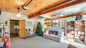 A cozy living room with a wooden ceiling, a Christmas tree, a sofa, and a bookshelf.