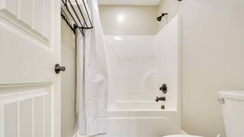 A bathroom with a bathtub, toilet, and a shower curtain.