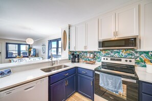 Una cocina moderna con armarios blancos y azul marino, un microondas, un horno y un lavavajillas.
