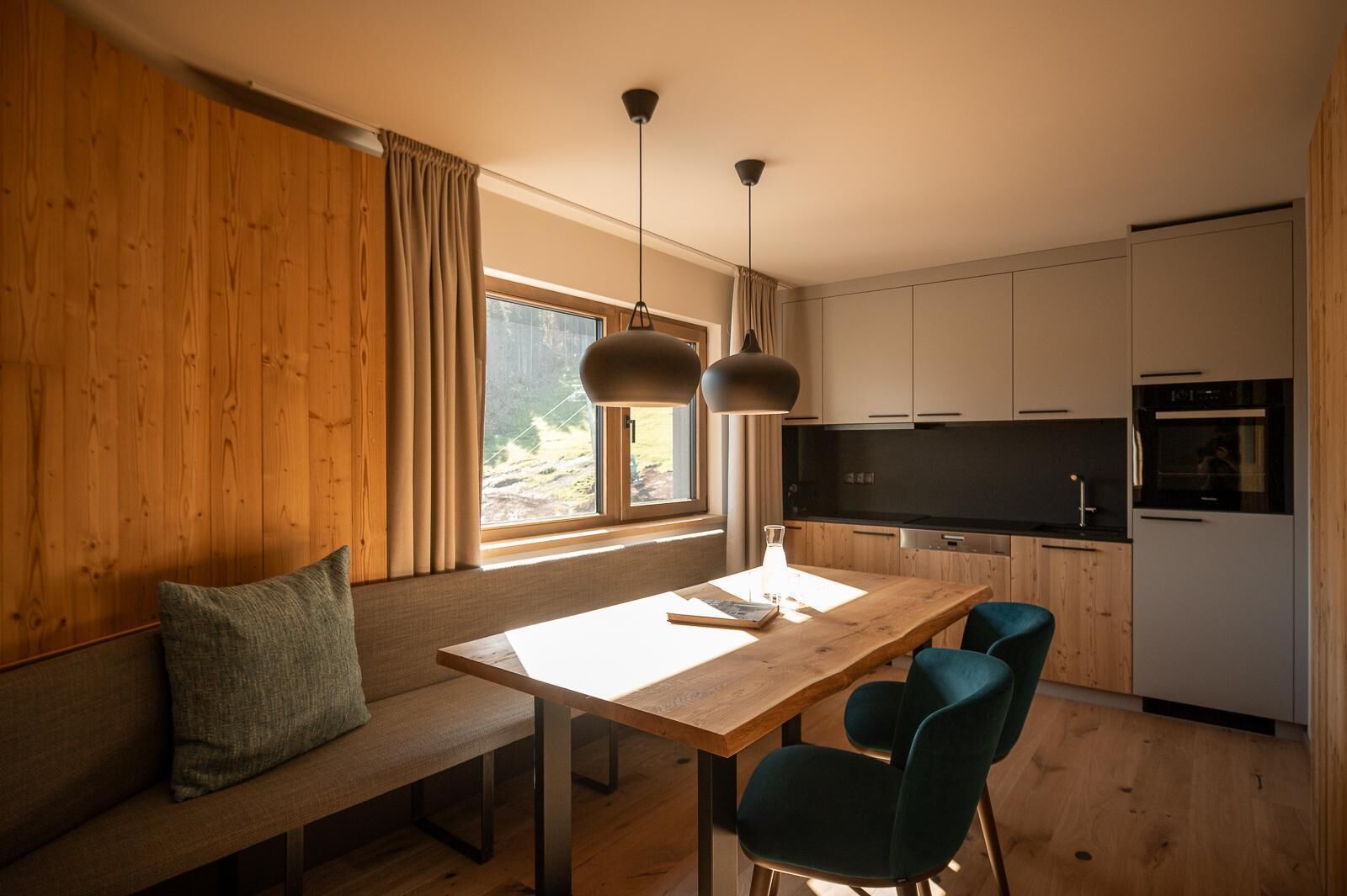 Eine moderne Küche mit Holzausstattung, einem Esstisch und zwei Stühlen.