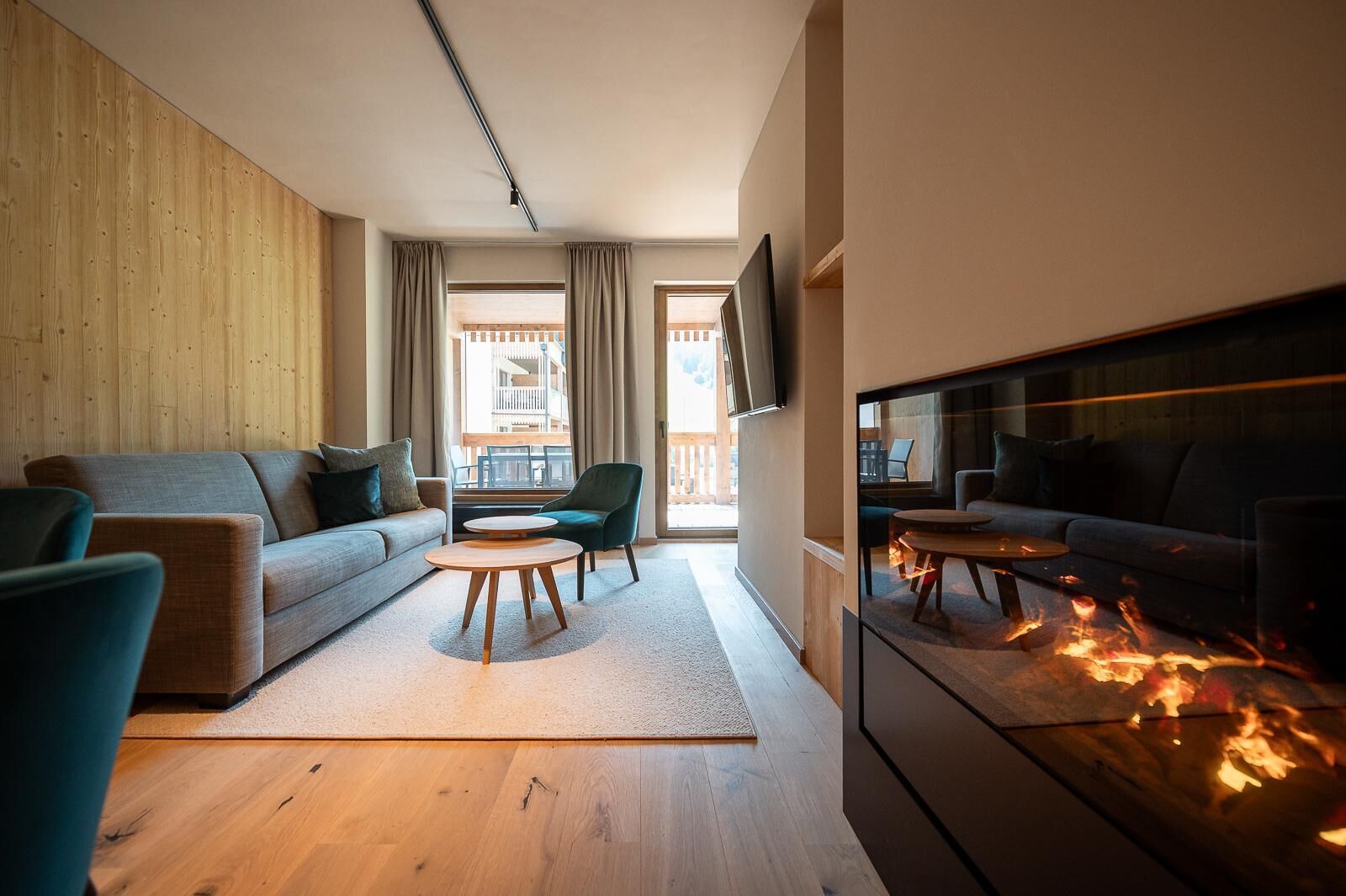 A modern living room with a fireplace, a sofa, a chair, and a television.