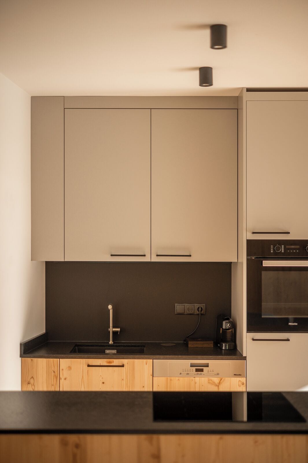 Een moderne keuken met houten kastjes, een zwart aanrecht en een ingebouwde oven.