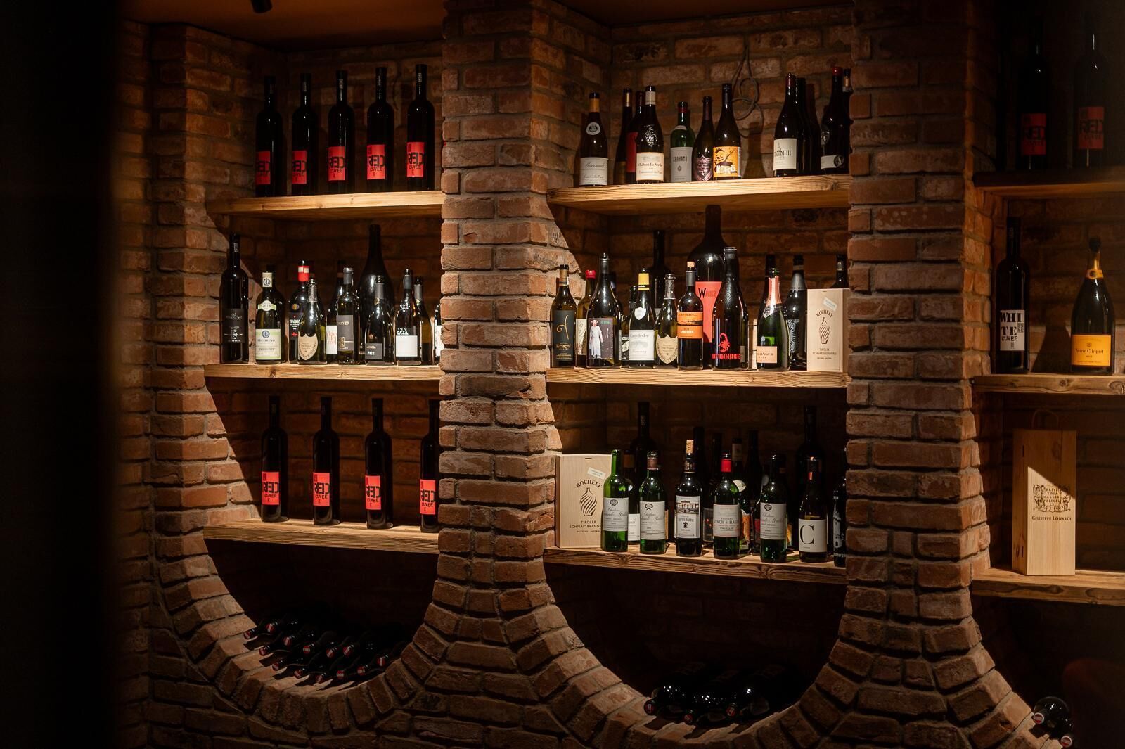 A wine cellar with multiple shelves and a brick column structure.