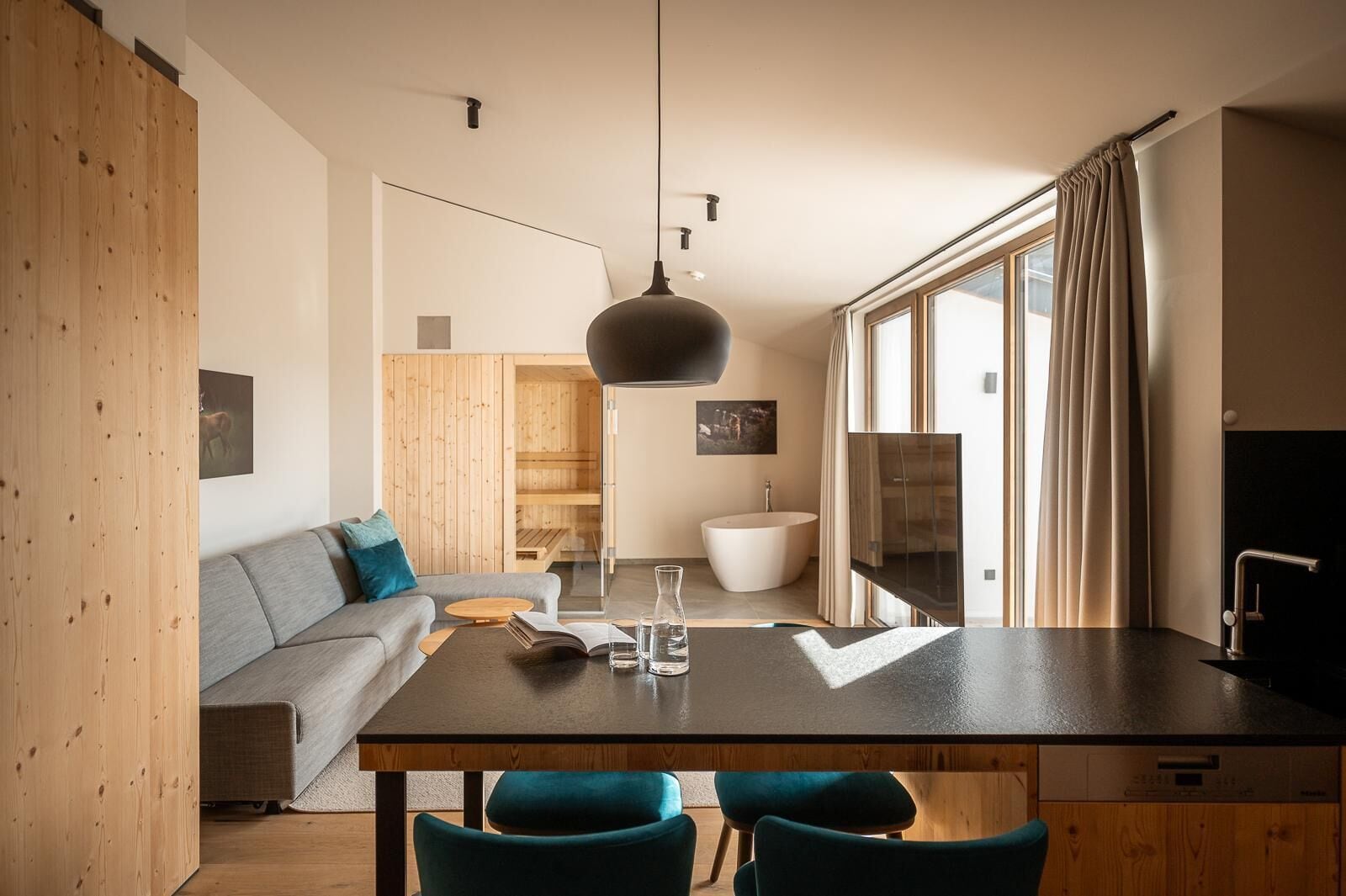Una cocina moderna con encimera oscura, armarios de madera y sillas color turquesa.