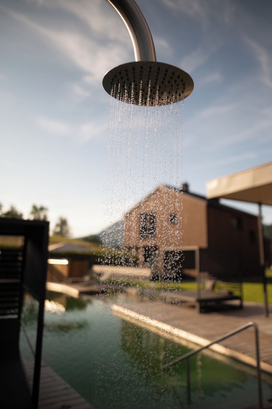 A showerhead with water flowing into a pool.