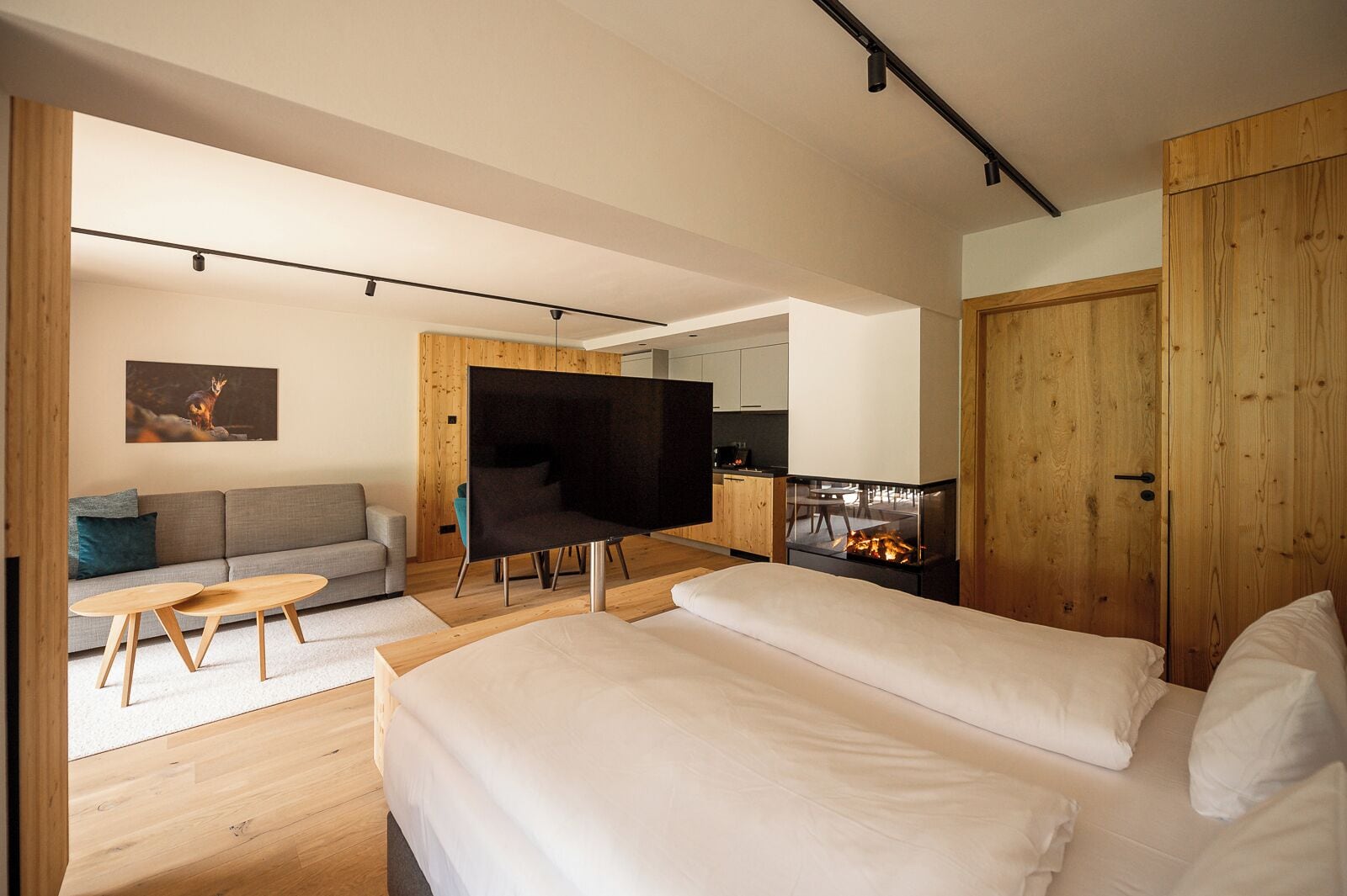 Een moderne slaapkamer met een groot bed, een televisie, een bank en een open haard.