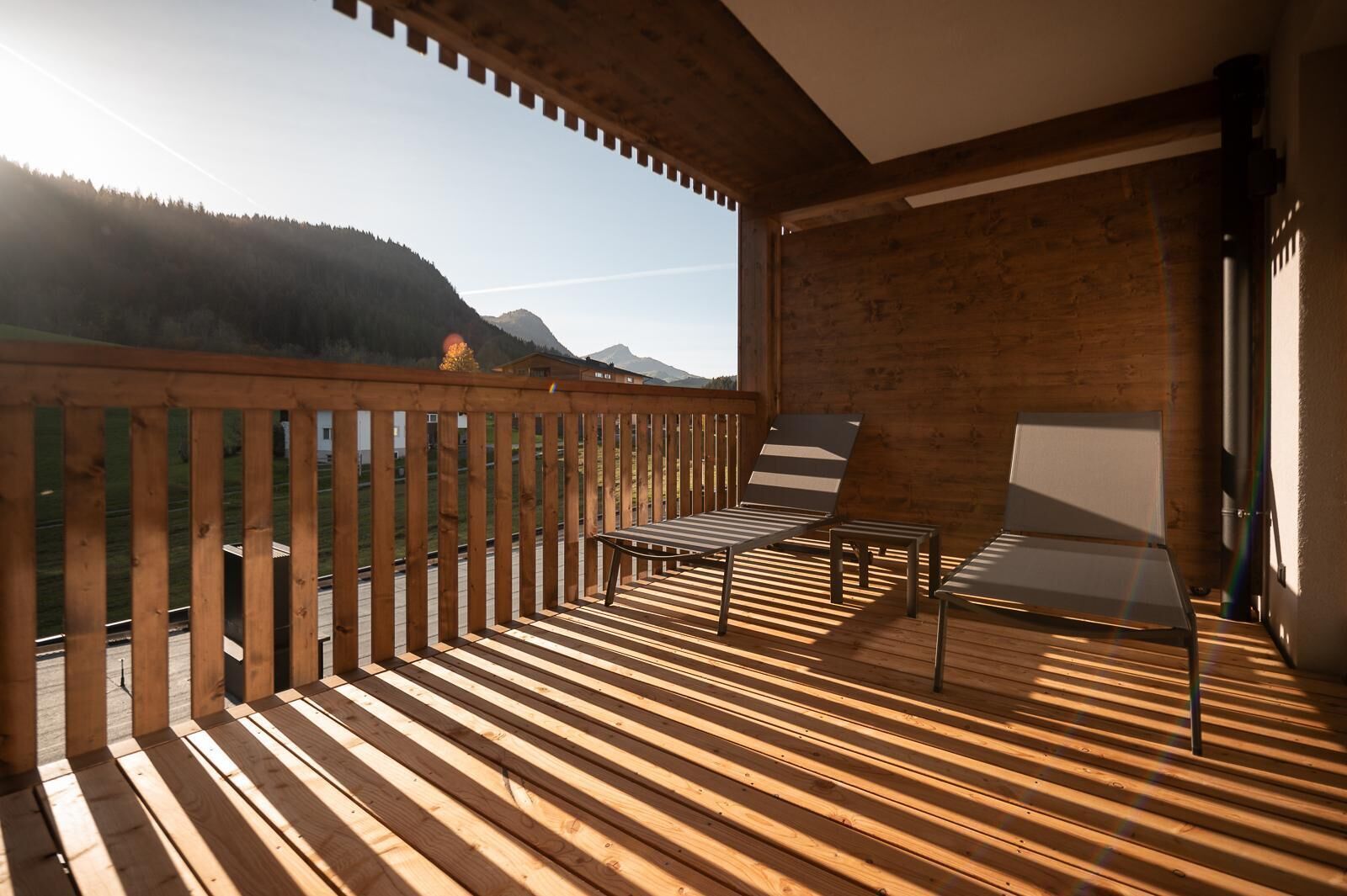 A wooden deck with a view of a forest and mountains.